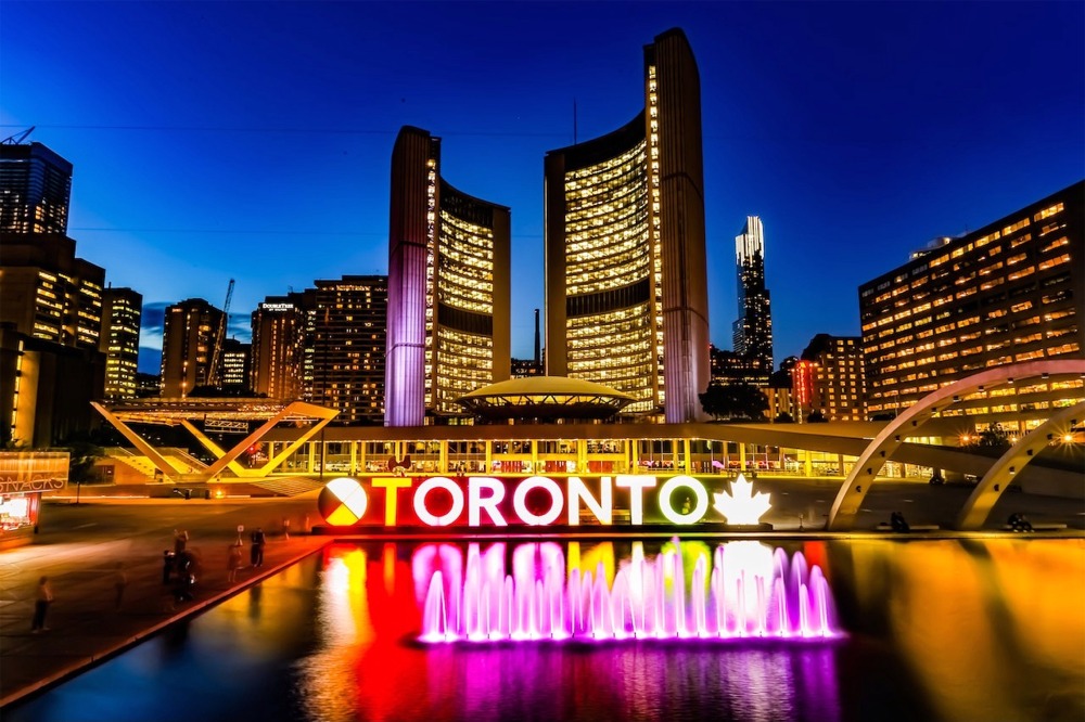 This is a photograph of the new City Hall, the Toronto Star Stage, the reflecting pool, and the 3D Toronto sign in Nathan Phillips Square, Toronto, Ontario, Canada.