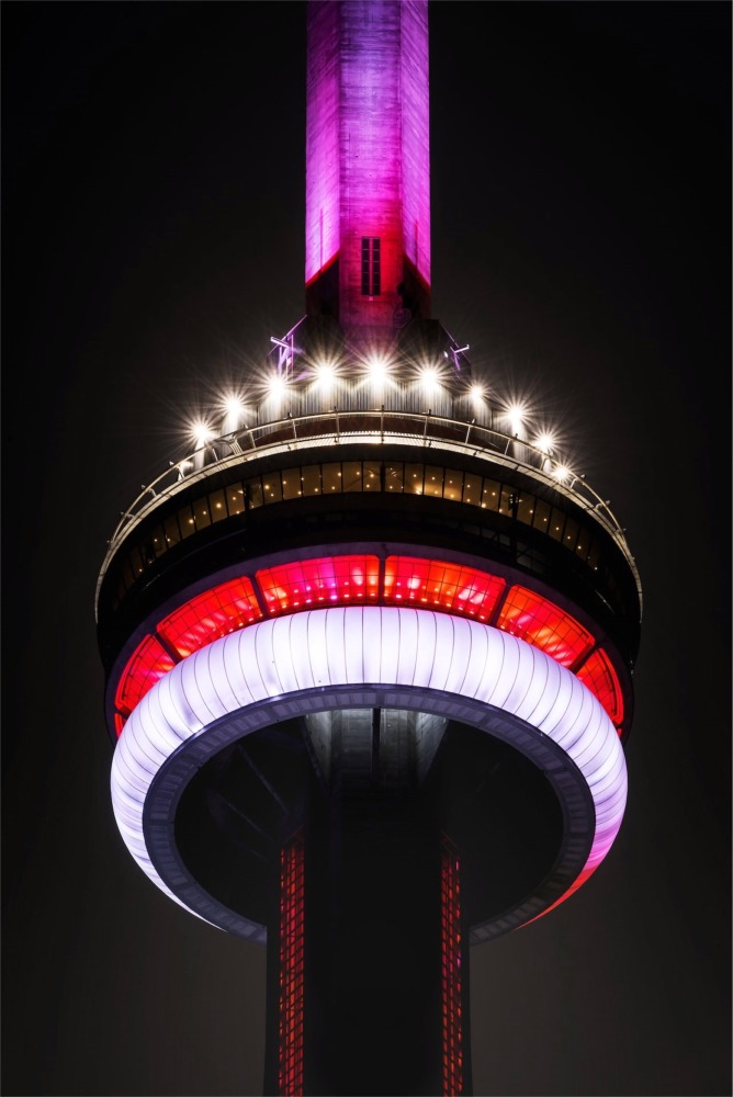 A close-up photograph of the CN Tower illuminated at nighttime in Toronto, Ontario, Canada.