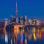 Toronto skyline at nighttime with a lovely reflection of the colored city lights in Lake Ontario.