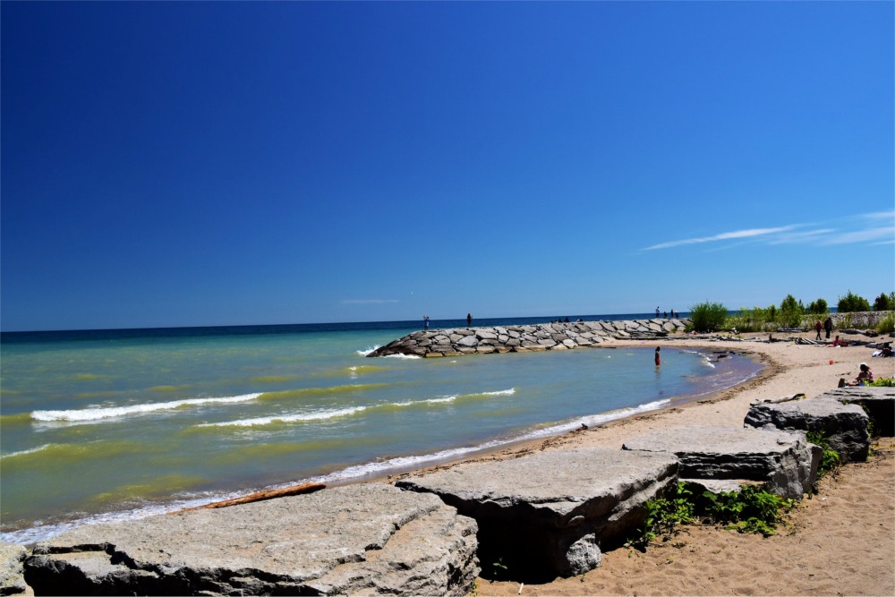 Photograph of people walking at the beach of Lake Ontario in the Rouge National Urban Park, Toronto, Ontario, Canada.