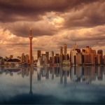 Toronto skyline with Lake Ontario in the foreground. Roger's Centre and the CN Tower feature in the middle of the image.