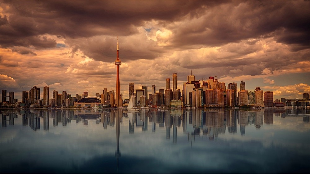Photograph of the Toronto skyline with Lake Ontario in the foreground. Roger's Centre and the CN Tower feature in the middle of the image.
