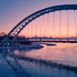 Humber Bay Arch Bridge. In the winter photo, we can see the CN tower through the arch and a cyclist on the bridge.