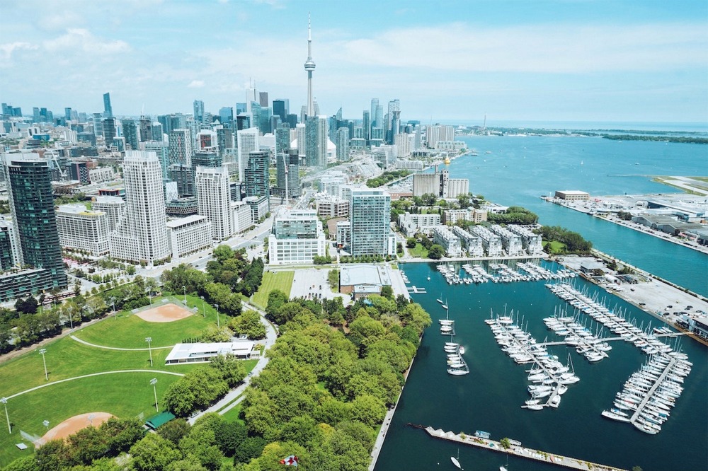 Photograph of the downtown Toronto Ontario Canada cityscape. We see Coronation Park and the Alexandra Yacht Club and Marina in the foreground.