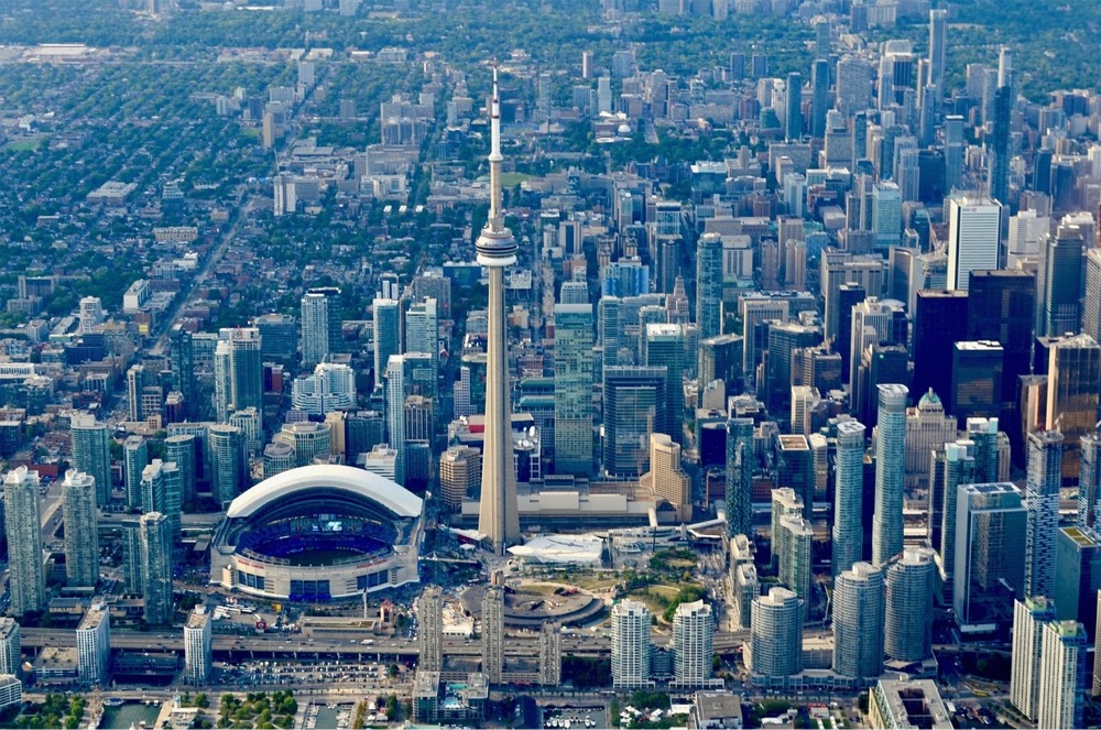 The downtown Toronto Ontario cityscape featuring the CN Tower, the Rogers Centre, the Round House Park & Toronto Railway Museum, and the Ripley's Aquarium of Canada.