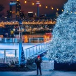 The Ontario Place Ice Rink in winter near an illuminated tree with the CN Tower in the background.